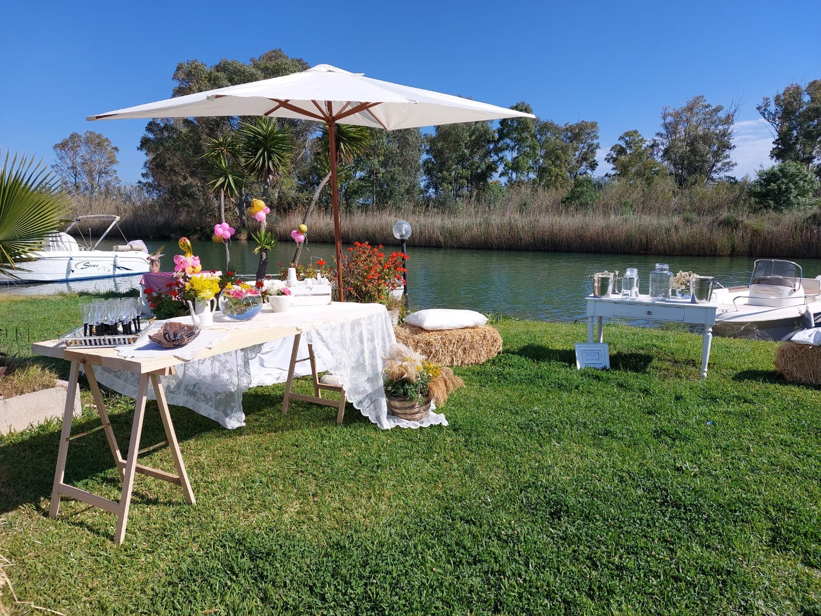 Tavola imbandita sul fiume con fiori e ombrellone